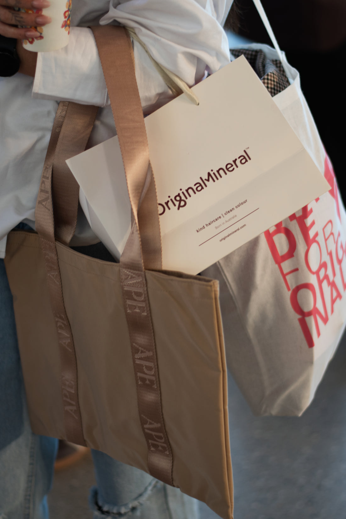 A beige mini tote bag with pink straps and a signature Ape strap detailing, placed against a white background.